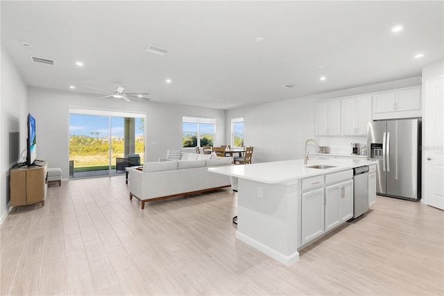 kitchen with appliances with stainless steel finishes, white cabinetry, a kitchen island with sink, and sink