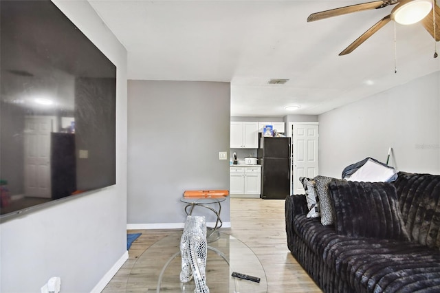 living room with ceiling fan and light hardwood / wood-style flooring