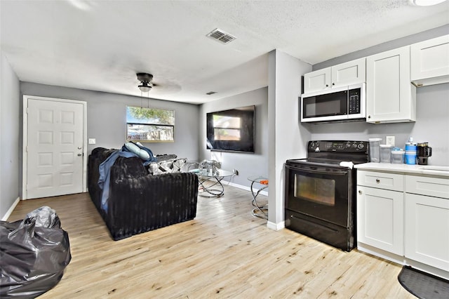 kitchen featuring white cabinets, light wood-type flooring, a textured ceiling, and black / electric stove