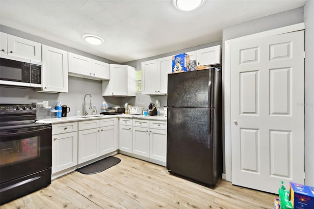 kitchen with black appliances, light hardwood / wood-style floors, white cabinetry, and sink