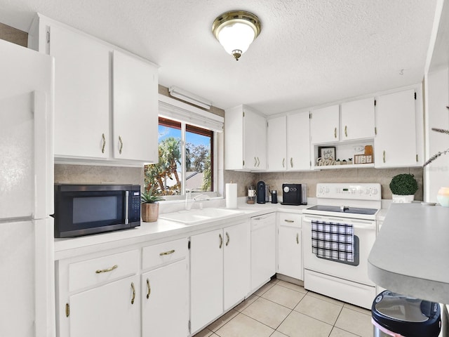 kitchen with a textured ceiling, white appliances, sink, light tile patterned floors, and white cabinetry