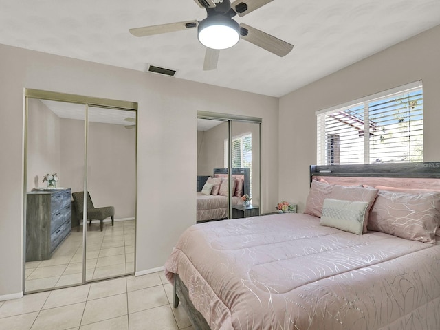 tiled bedroom featuring ceiling fan and multiple closets