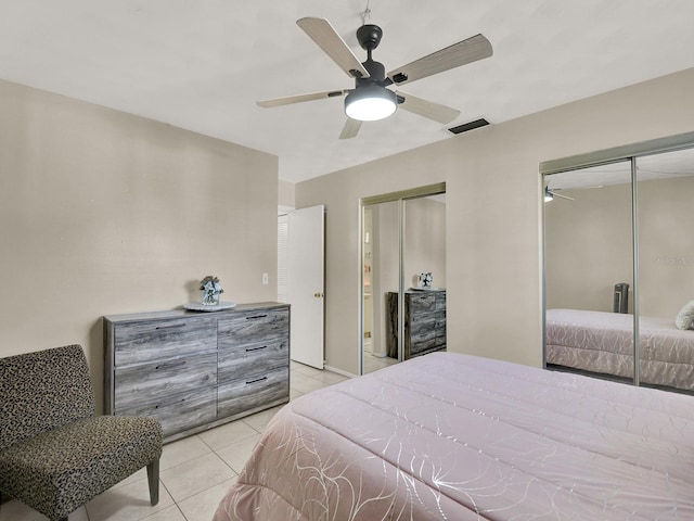 tiled bedroom featuring multiple closets and ceiling fan