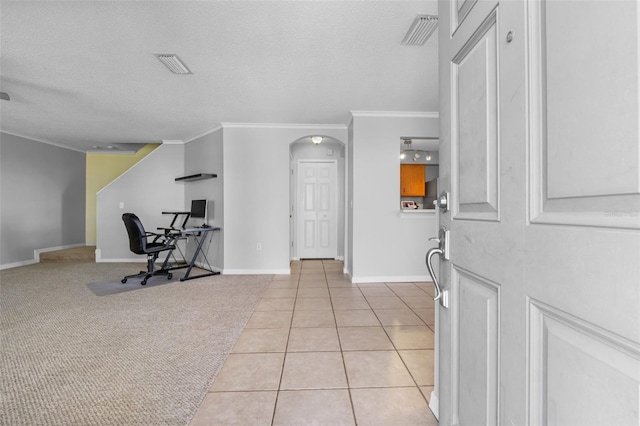 tiled entrance foyer with a textured ceiling and ornamental molding