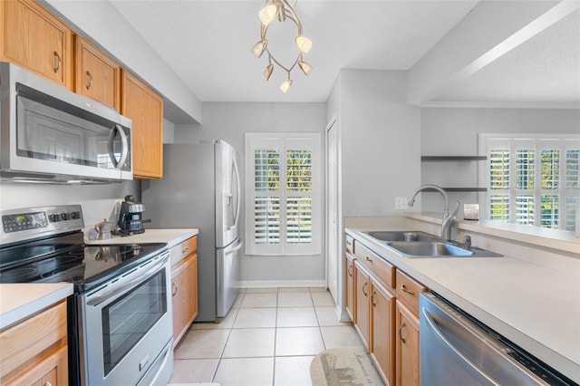 kitchen with a healthy amount of sunlight, sink, light tile patterned floors, and stainless steel appliances