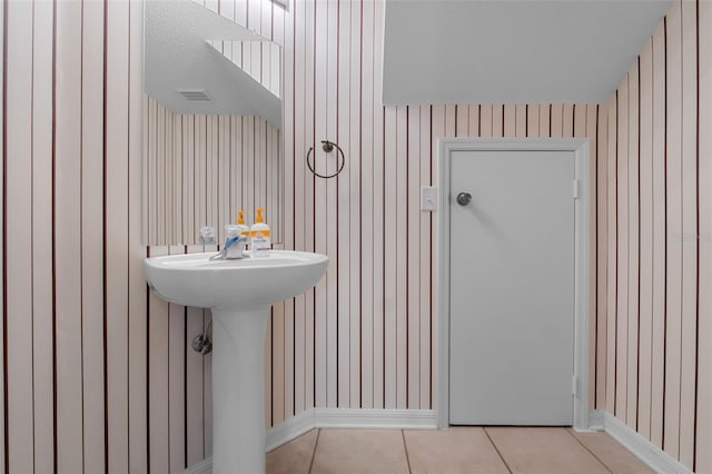 bathroom with tile patterned flooring, wooden walls, and sink