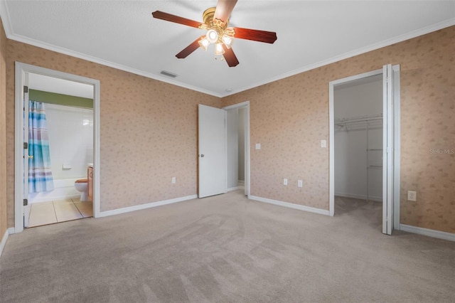 unfurnished bedroom featuring light colored carpet, ensuite bath, ceiling fan, and ornamental molding