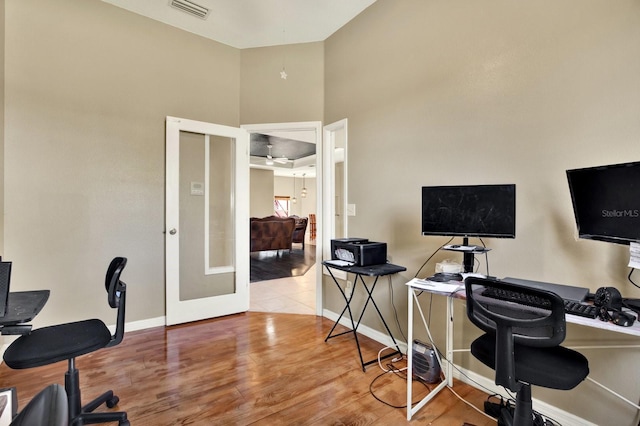 office with light wood-type flooring, french doors, and a towering ceiling