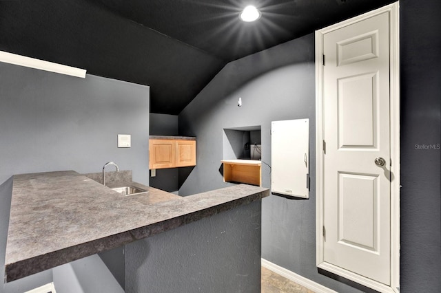 kitchen with light brown cabinets, kitchen peninsula, sink, and vaulted ceiling