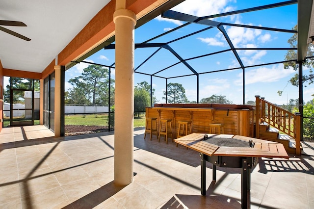 view of patio / terrace with ceiling fan, a lanai, exterior bar, and a hot tub