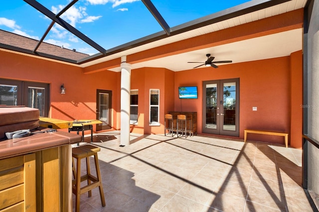 view of patio featuring french doors, a hot tub, glass enclosure, and ceiling fan