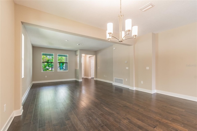 spare room with dark hardwood / wood-style flooring and an inviting chandelier