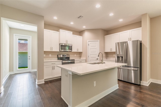 kitchen with appliances with stainless steel finishes, sink, white cabinets, dark hardwood / wood-style floors, and an island with sink