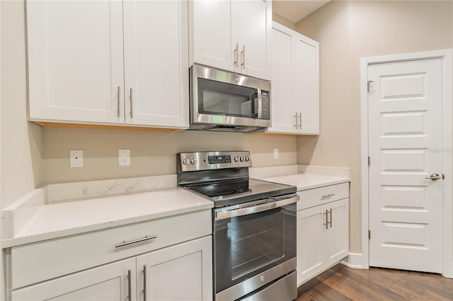 kitchen with light stone countertops, white cabinets, dark wood-type flooring, and appliances with stainless steel finishes