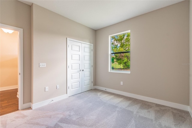 unfurnished bedroom with light carpet and a closet