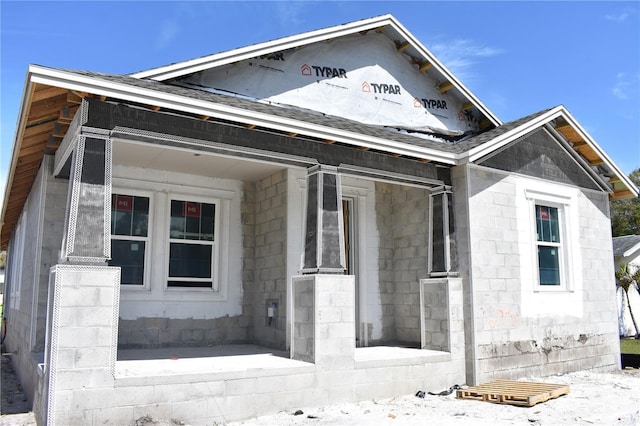 view of front facade with concrete block siding and roof with shingles