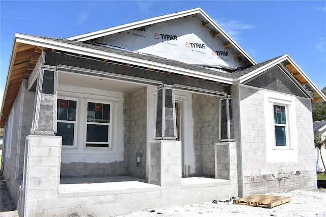 view of front of home with a shingled roof and concrete block siding