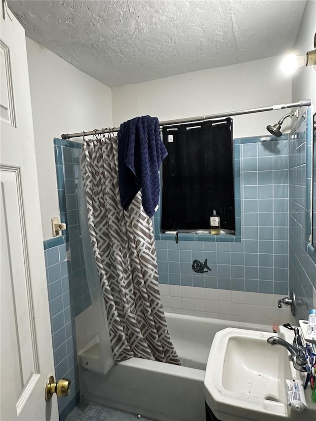 bathroom with shower / bath combination with curtain, sink, and a textured ceiling