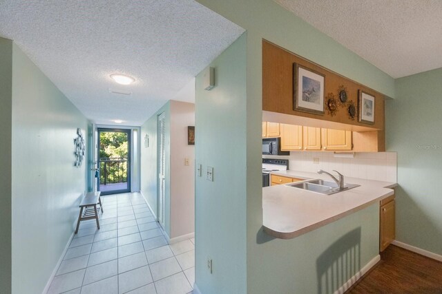 9433 Harbor Greens Way Unit 403, Seminole, FL 33776 - kitchen featuring white electric stove, a sink, black microwave, a textured ceiling, and light countertops