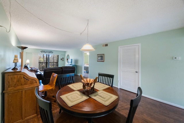 dining area featuring a textured ceiling and dark wood-type flooring