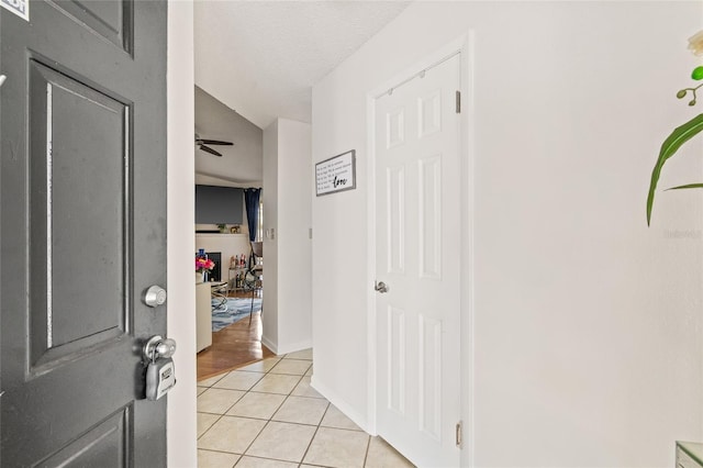 foyer entrance with ceiling fan, light tile patterned flooring, and a textured ceiling