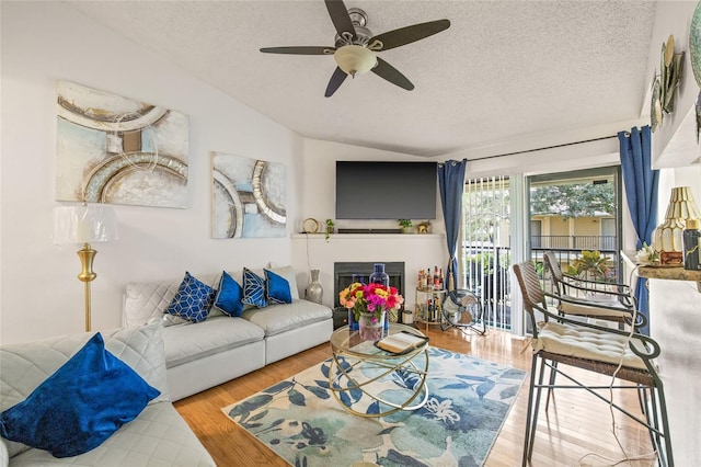 living room featuring a textured ceiling, ceiling fan, vaulted ceiling, and hardwood / wood-style flooring