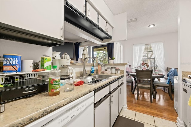 kitchen with white cabinets, light wood-type flooring, white dishwasher, and sink