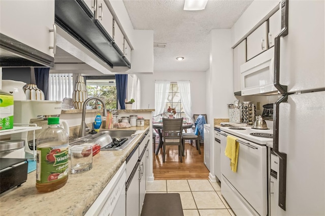 kitchen featuring sink, a textured ceiling, white appliances, white cabinets, and light wood-type flooring