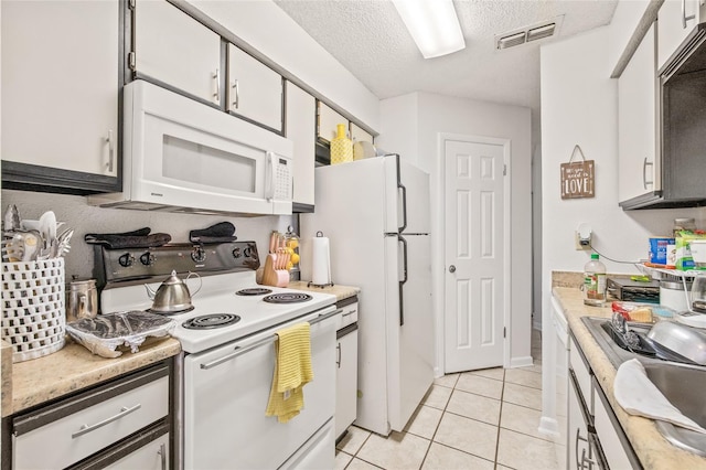 kitchen featuring a textured ceiling, white cabinetry, and white appliances