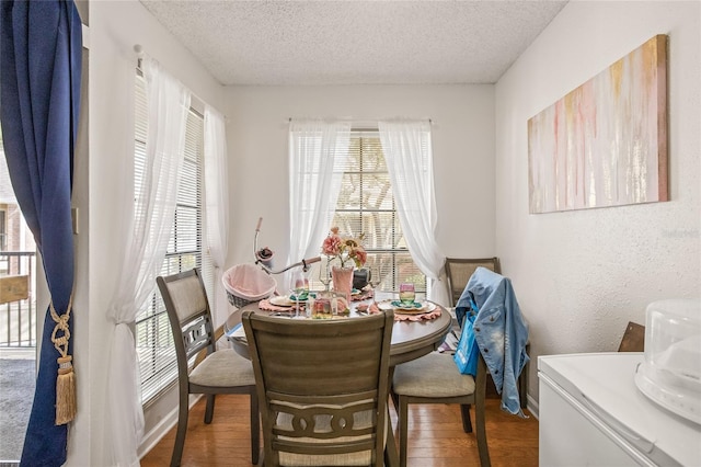 dining space with wood-type flooring, a textured ceiling, and a healthy amount of sunlight