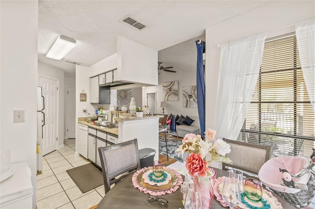 dining space featuring ceiling fan, light tile patterned floors, and a textured ceiling