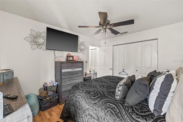 bedroom with ceiling fan, a closet, a textured ceiling, and light wood-type flooring