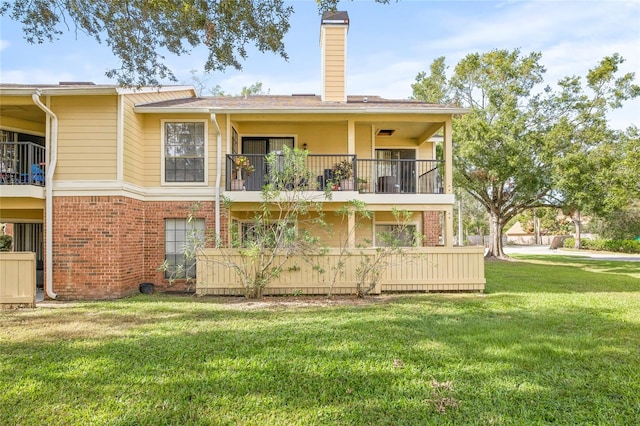 8722 Mallard Reserve Dr Unit 204, Tampa, FL 33614 - back of house featuring a balcony, brick siding, a chimney, and a lawn
