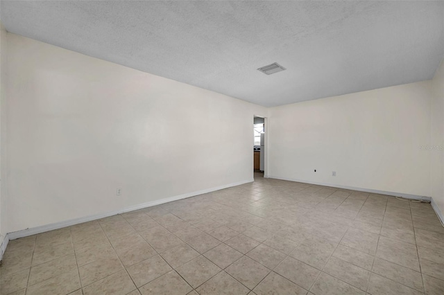 tiled spare room featuring a textured ceiling