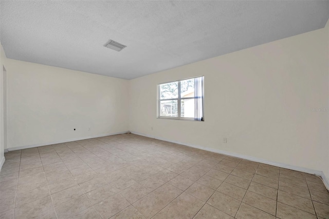 spare room featuring light tile patterned floors and a textured ceiling