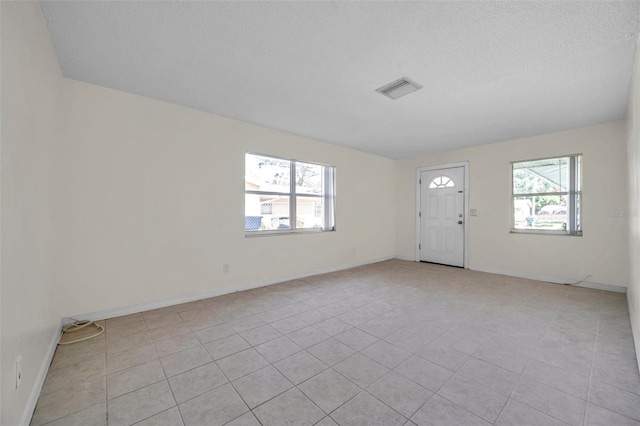 tiled foyer featuring plenty of natural light and a textured ceiling