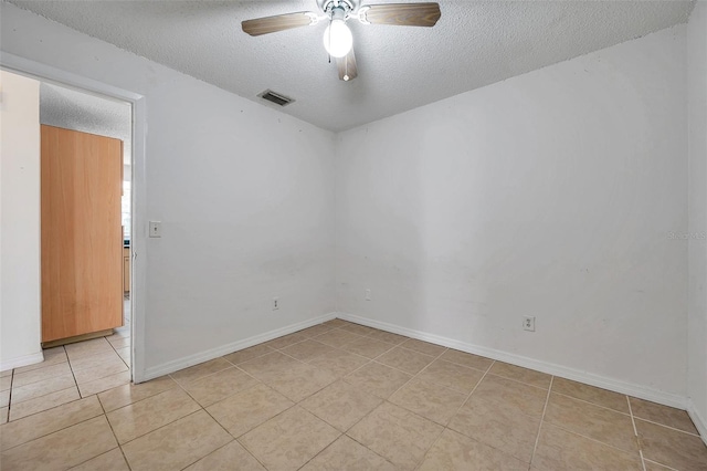 empty room with ceiling fan, light tile patterned floors, and a textured ceiling