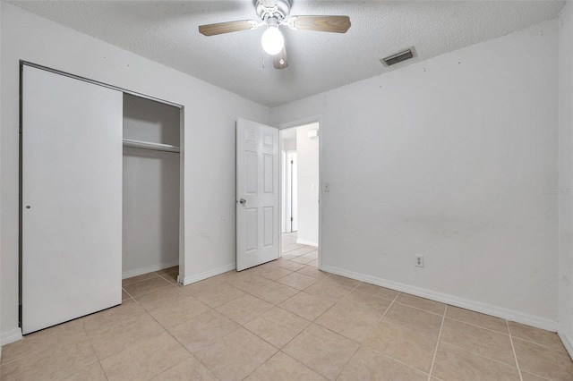 unfurnished bedroom with ceiling fan, a closet, light tile patterned floors, and a textured ceiling