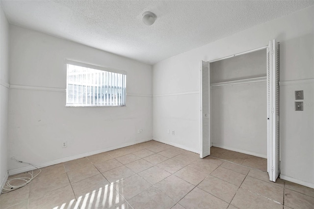 unfurnished bedroom featuring a closet, light tile patterned flooring, and a textured ceiling