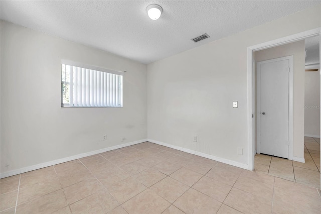 tiled empty room featuring a textured ceiling