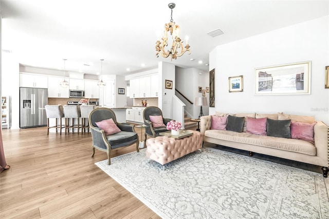 living room with light hardwood / wood-style floors and an inviting chandelier