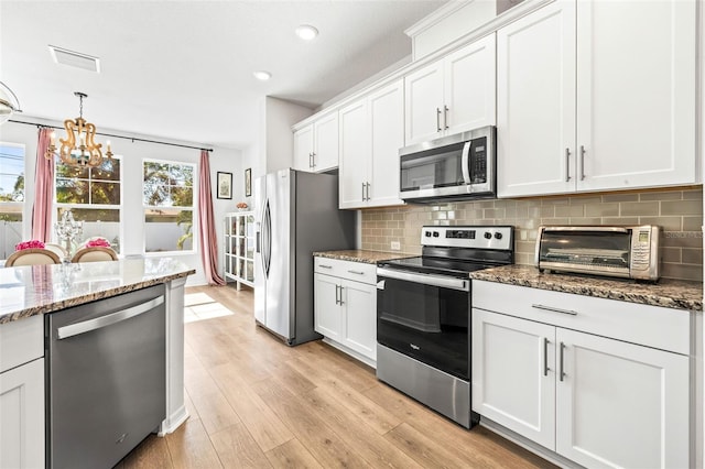 kitchen featuring stone countertops, light hardwood / wood-style floors, white cabinetry, and appliances with stainless steel finishes