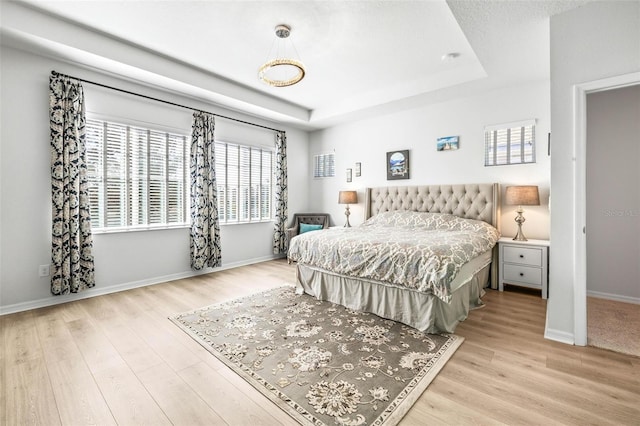 bedroom featuring a raised ceiling and light hardwood / wood-style flooring