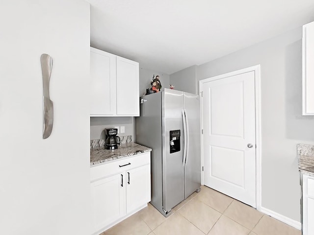 kitchen featuring white cabinets, light stone countertops, stainless steel refrigerator with ice dispenser, and light tile patterned floors