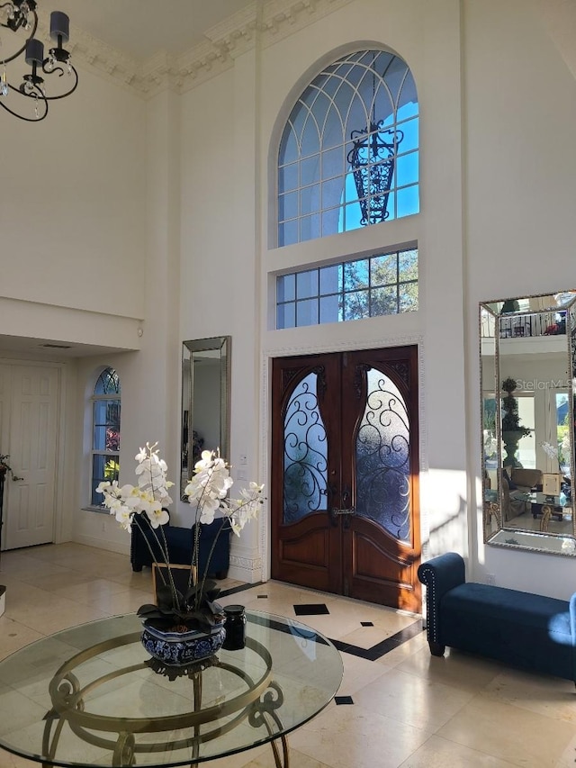 tiled entryway with french doors, a towering ceiling, and a healthy amount of sunlight