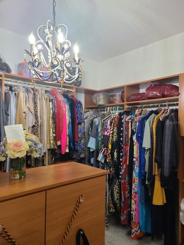 spacious closet featuring carpet flooring and an inviting chandelier