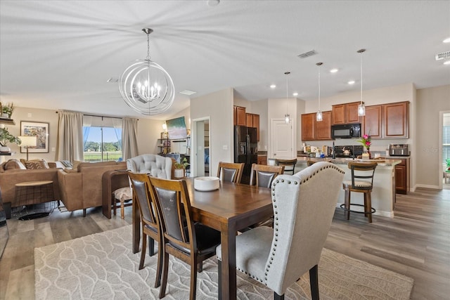 dining area with light hardwood / wood-style floors and a chandelier