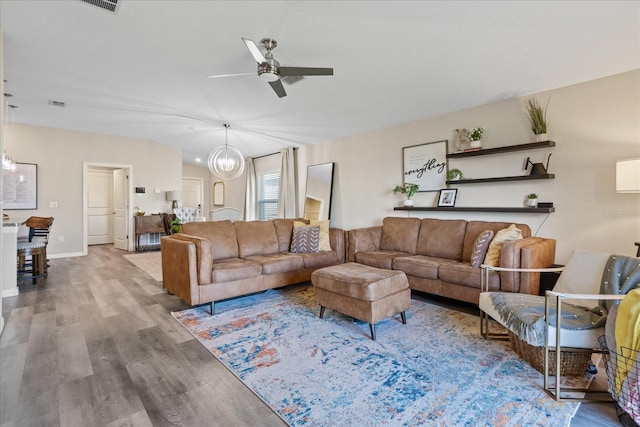 living room featuring ceiling fan with notable chandelier and hardwood / wood-style flooring