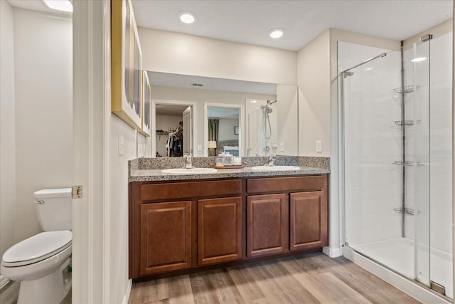 bathroom featuring hardwood / wood-style floors, vanity, toilet, and a shower with shower door