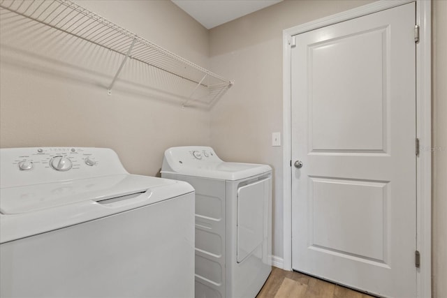 clothes washing area featuring washing machine and dryer and light hardwood / wood-style flooring